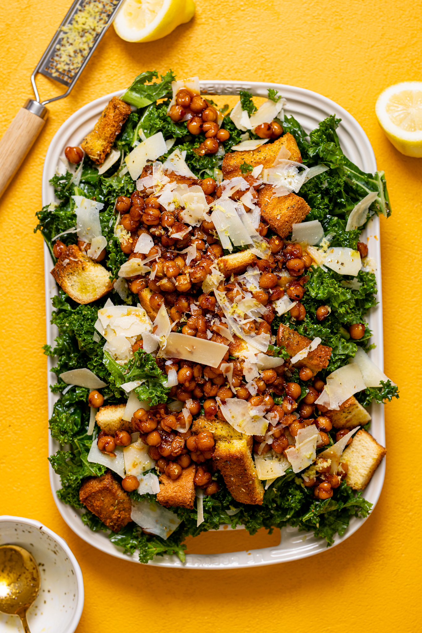 Lemon Parmesan Kale Salad with Hot Honey Chickpeas on a platter on a yellow table.