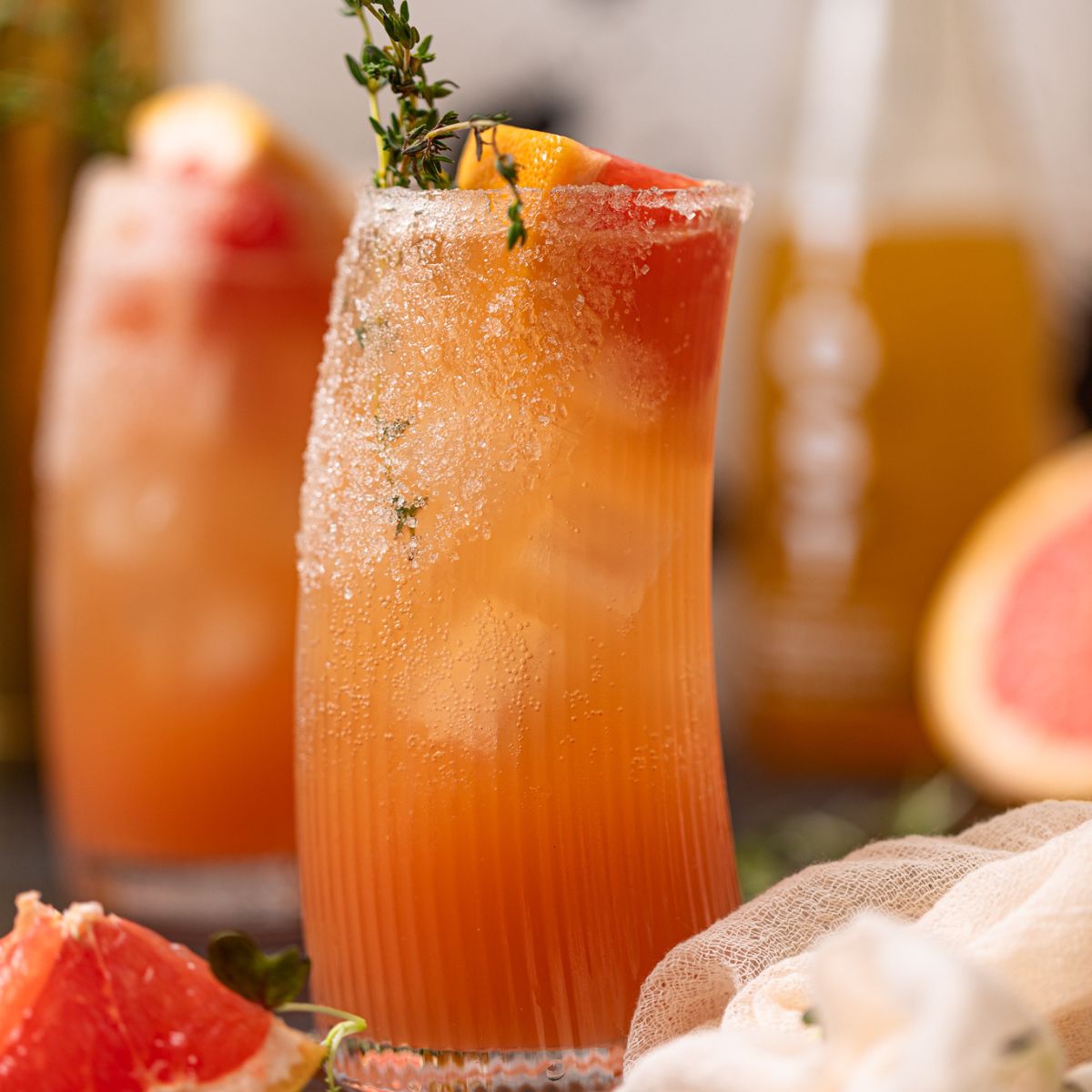 Two glasses of Grapefruit Aperol Spritz Mocktail with grapefruit wedges.