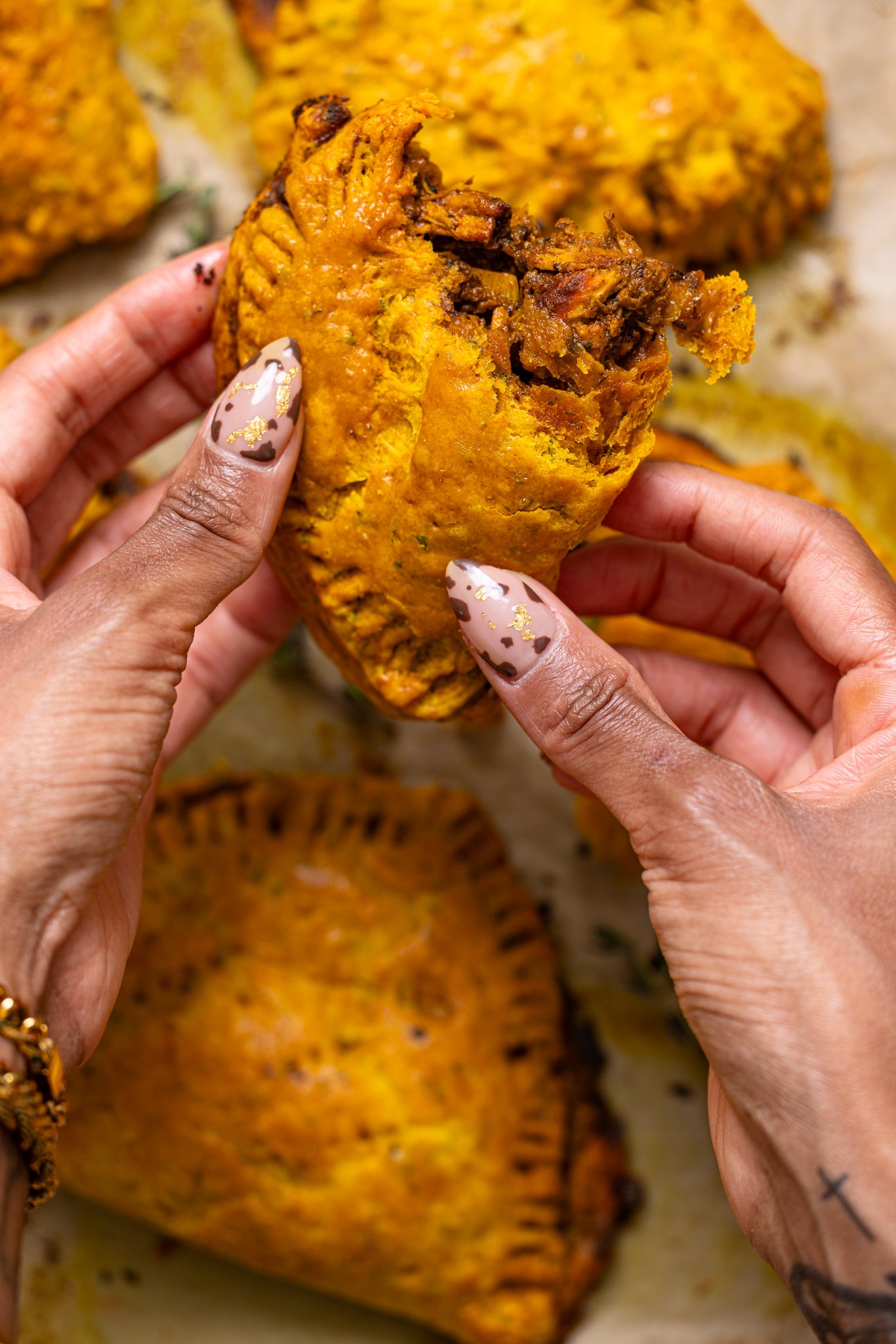 Image of Flaky Jamaican Curry Chicken Patties being held with woman hands.