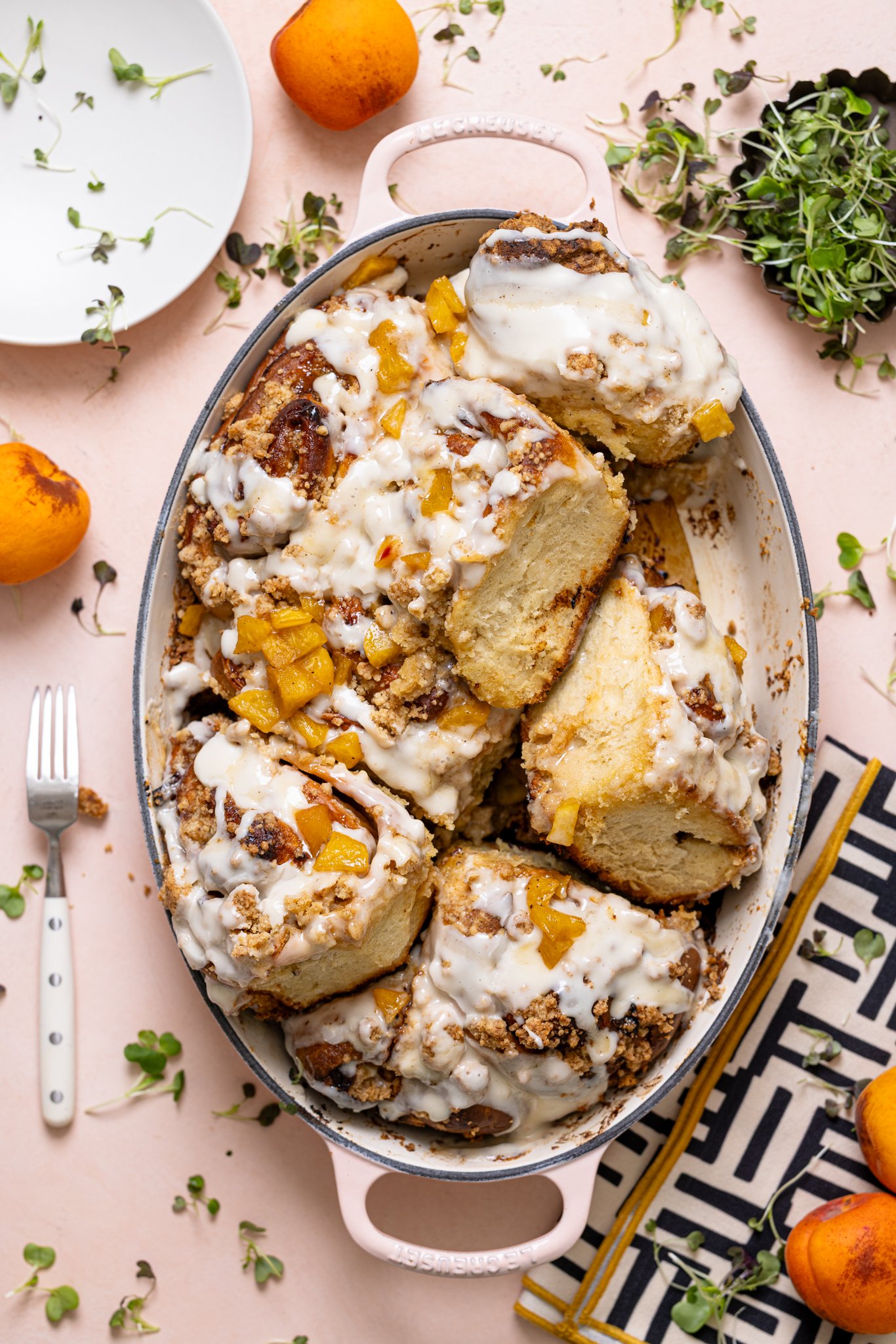 Southern Peach Cobbler Cinnamon Rolls in a baking dish with peaches.