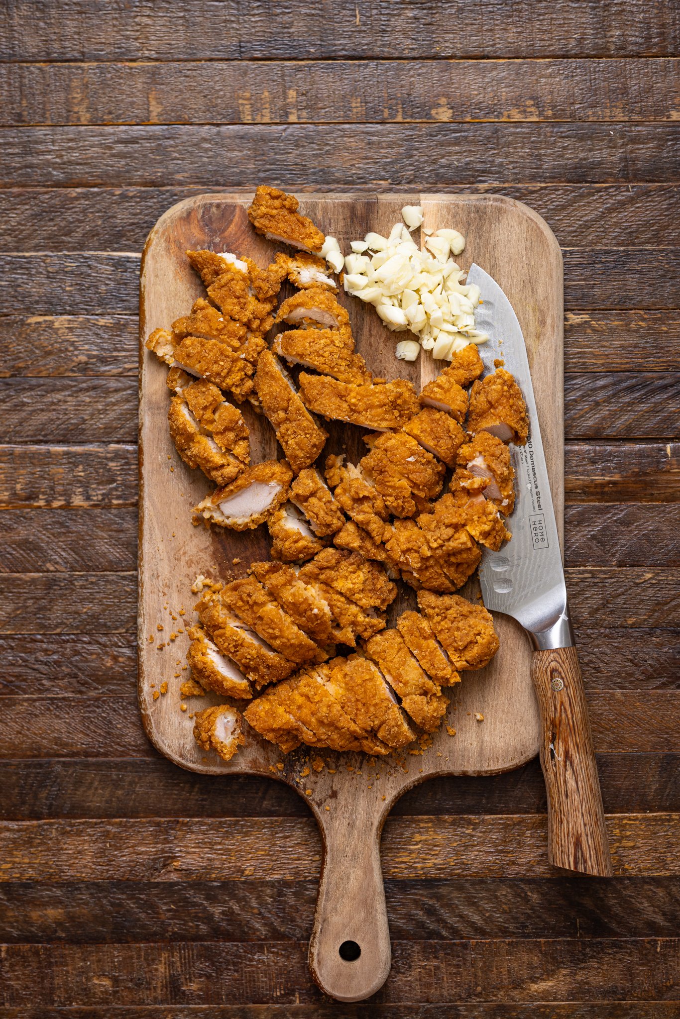 Chopped chicken pieces on a cutting board with a knife.