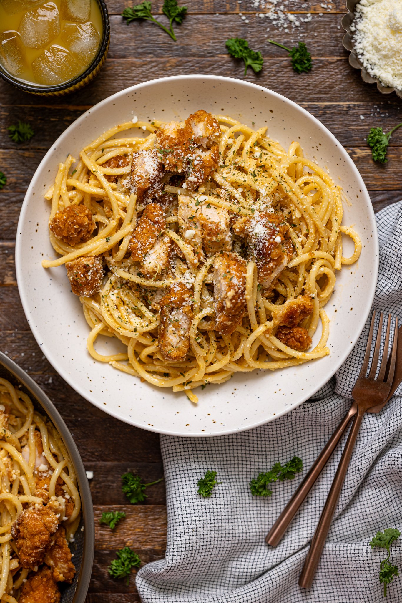 Southern Creamy Parmesan Garlic Chicken Pasta on a plate with a drink and garnish.