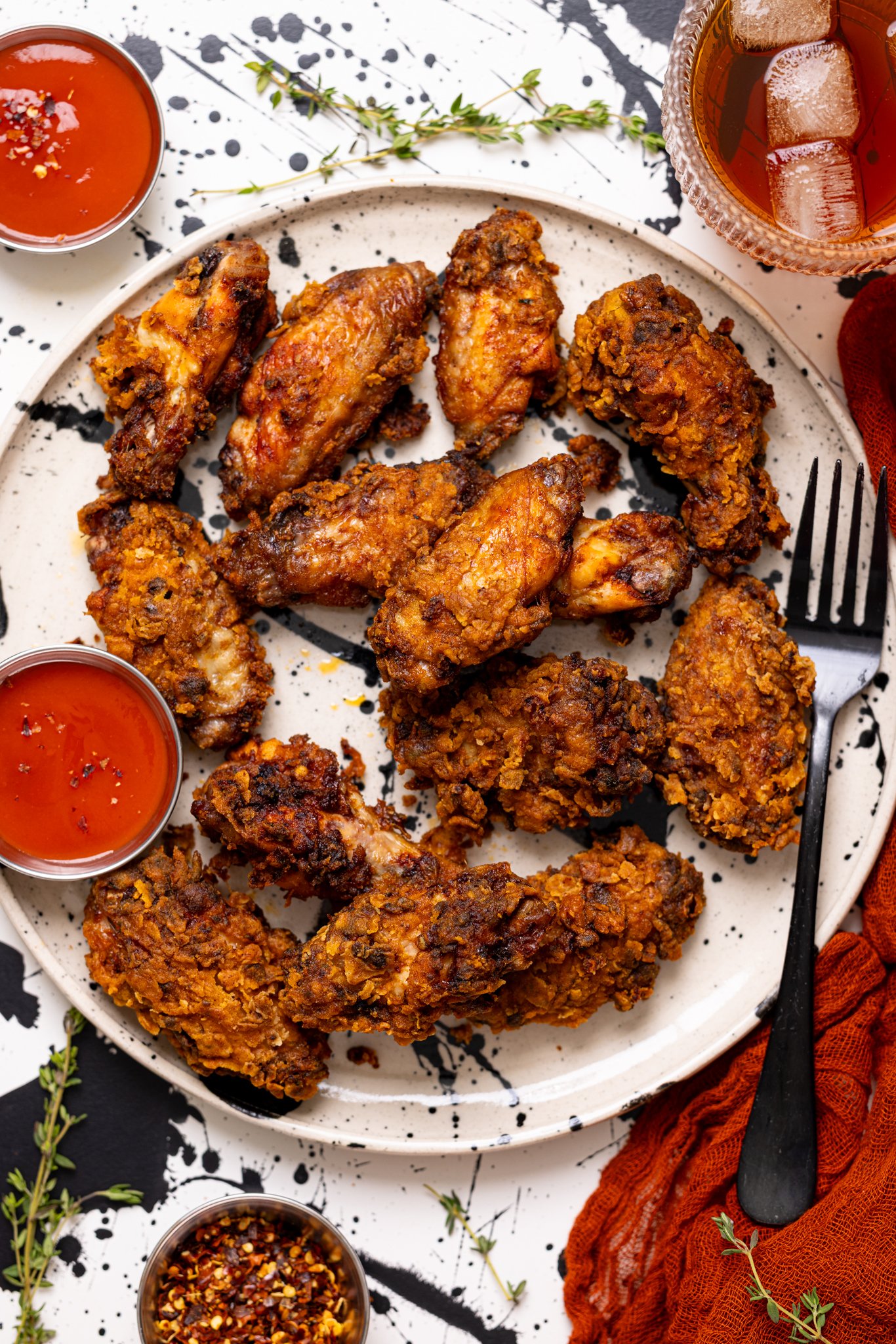 Crispy Spicy Fried Chicken Wings on a plate with a fork and hot sauce.