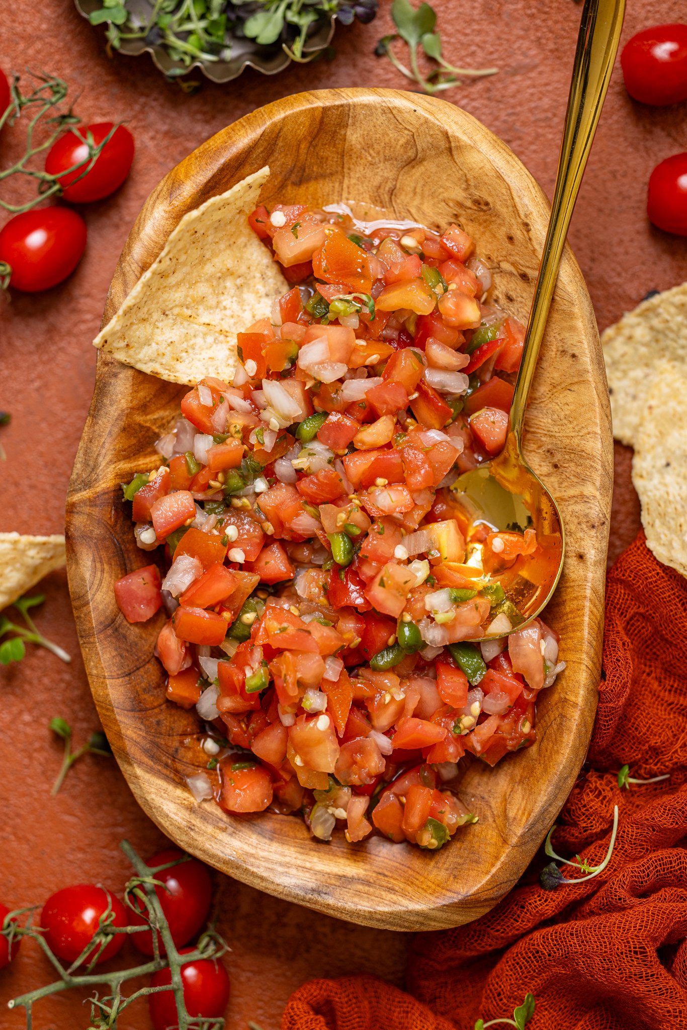 Fresh Pico de Gallo in a wooden bowl with a spoon and chips.