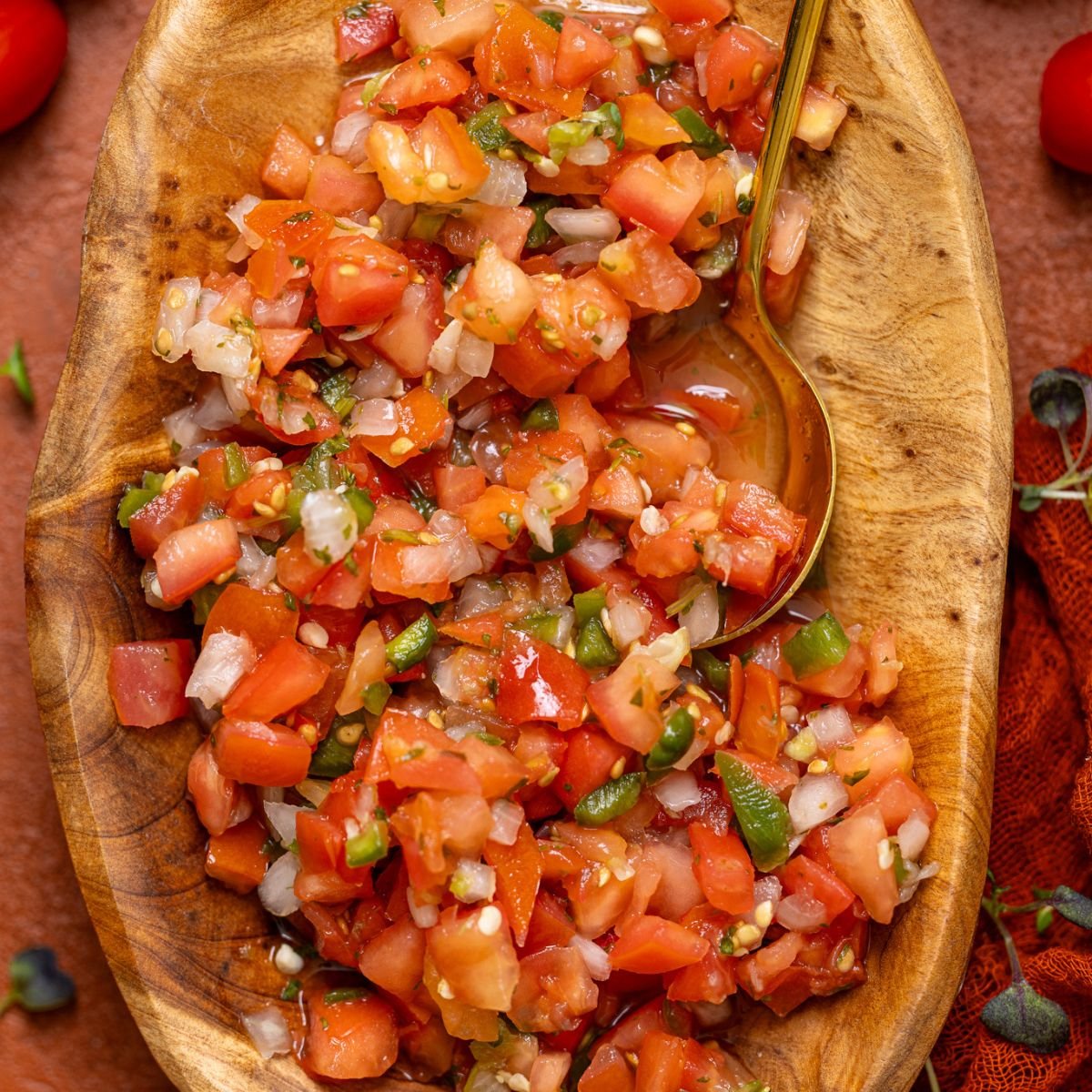 Up close shot of Fresh Pico de Gallo in a wooden bowl with a spoon.