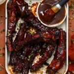 Hubby’s Favorite Oven-Baked BBQ Ribs on ceramic baking sheet with a side of drinks.