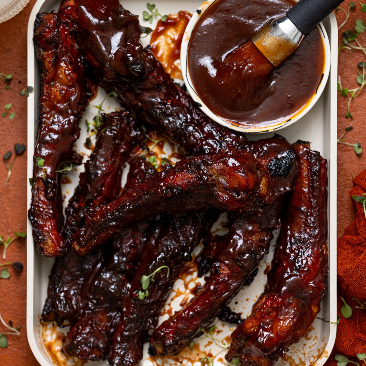 Hubby’s Favorite Oven-Baked BBQ Ribs on ceramic baking sheet with a side of drinks.