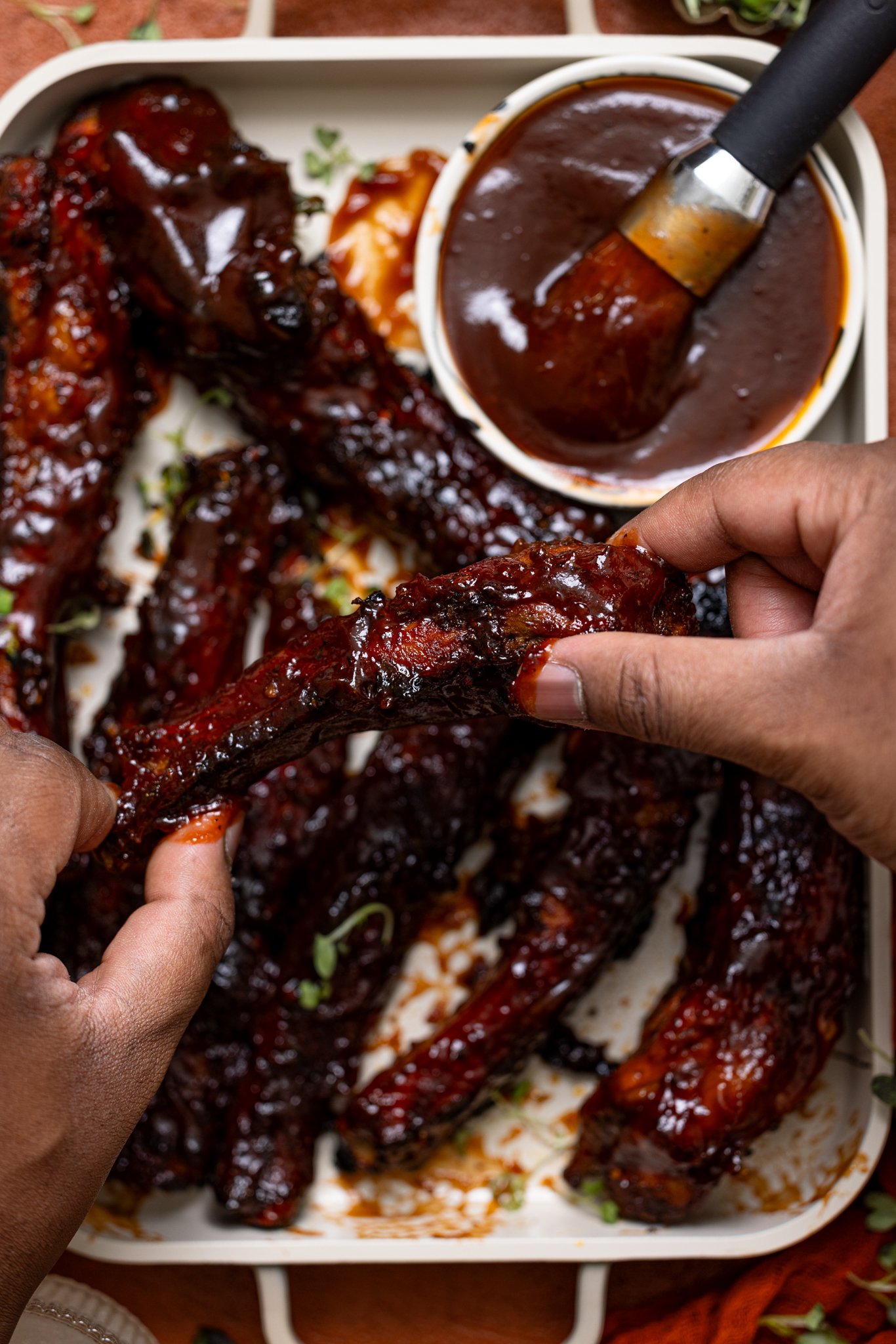 Hubby’s Favorite Oven-Baked BBQ Ribs being held by man hands.