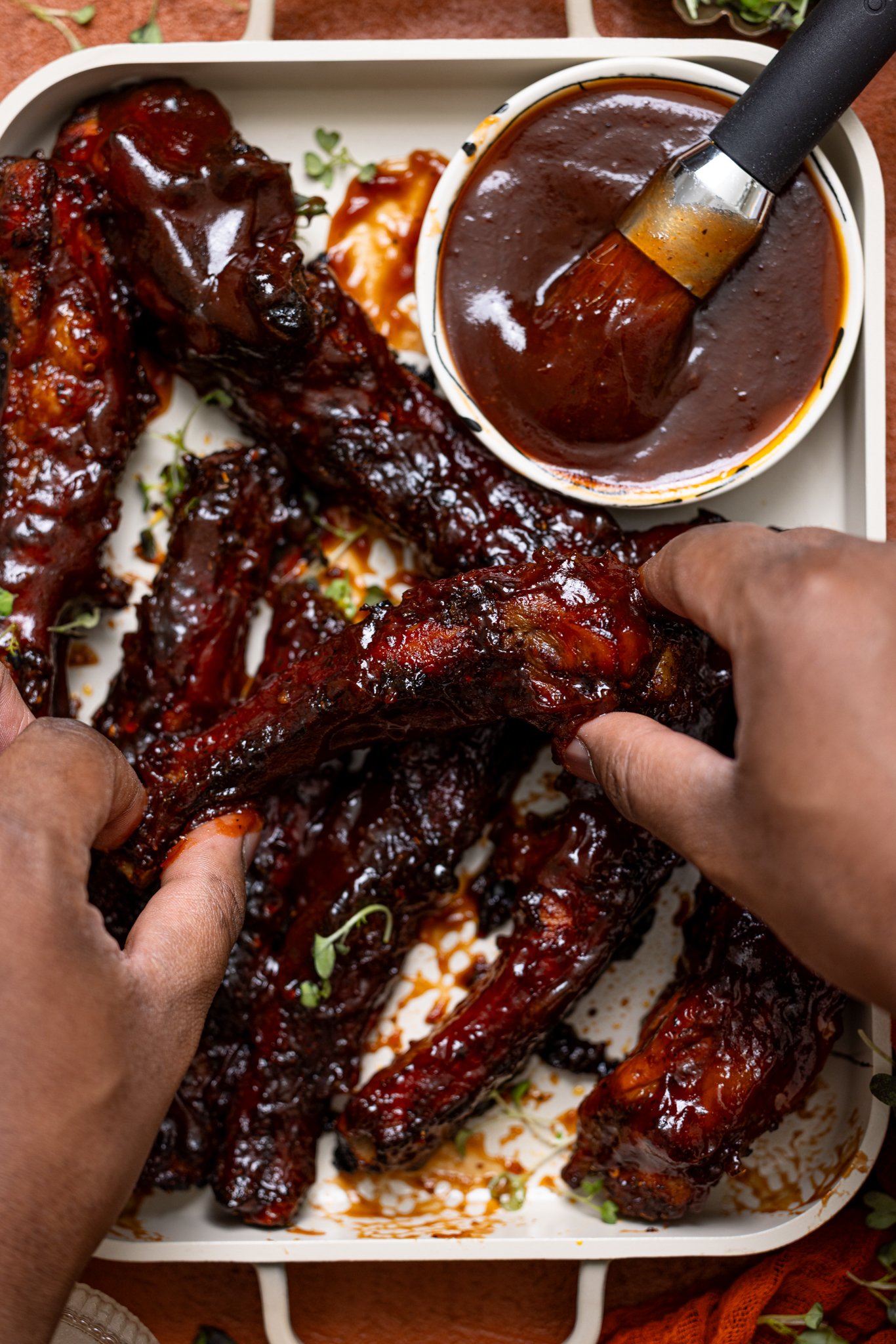 Hubby’s Favorite Oven-Baked BBQ Ribs being held by man hands.