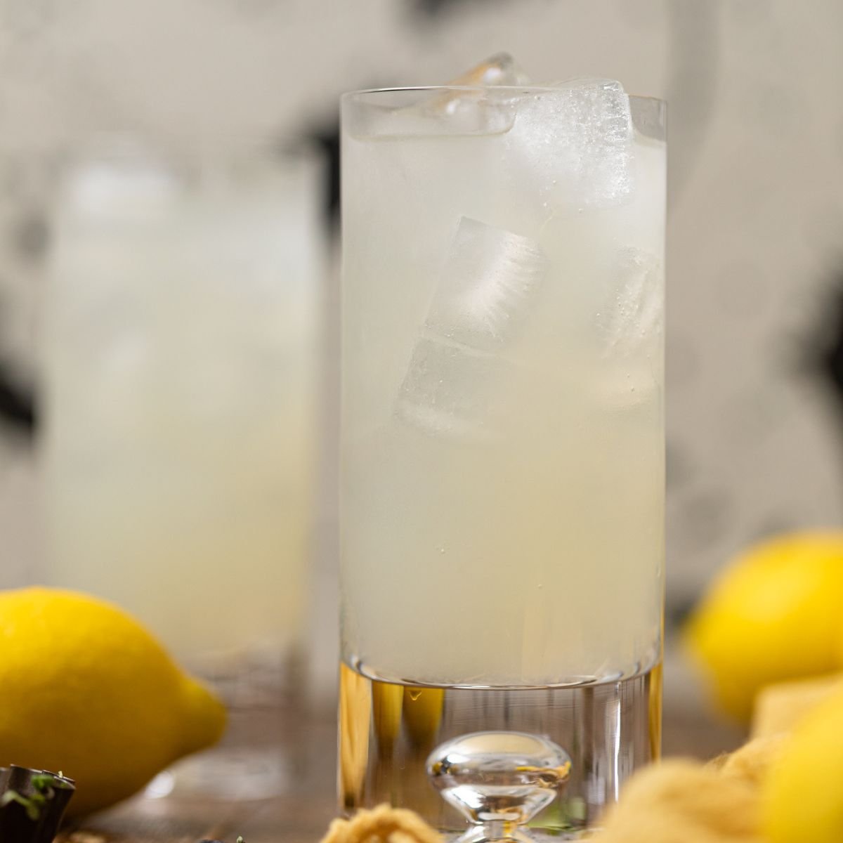 Refreshing Homemade Lemonade with lemons in the background.