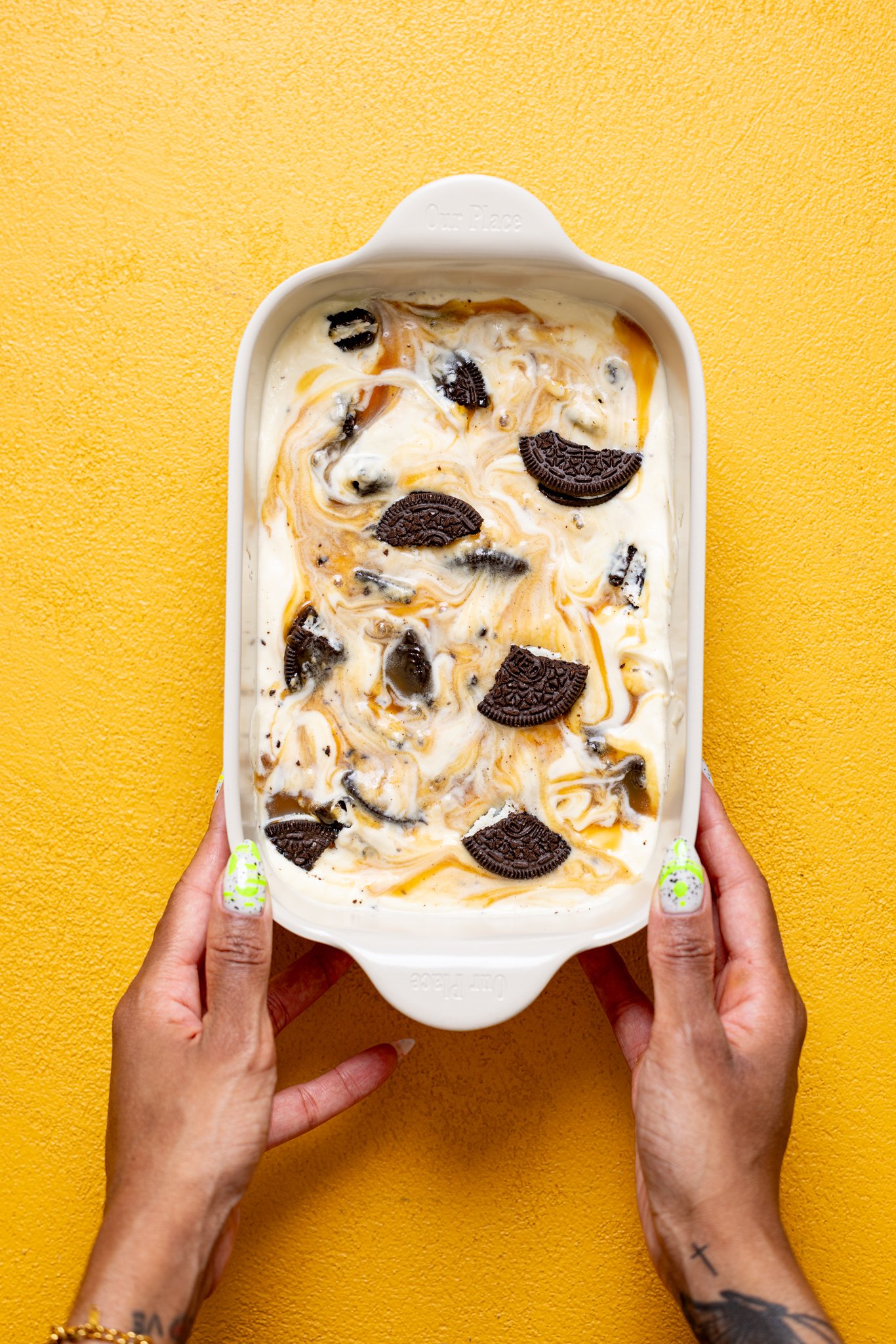 No-Churn Salted Caramel Oreo Ice Cream in a pan being held with woman hands.