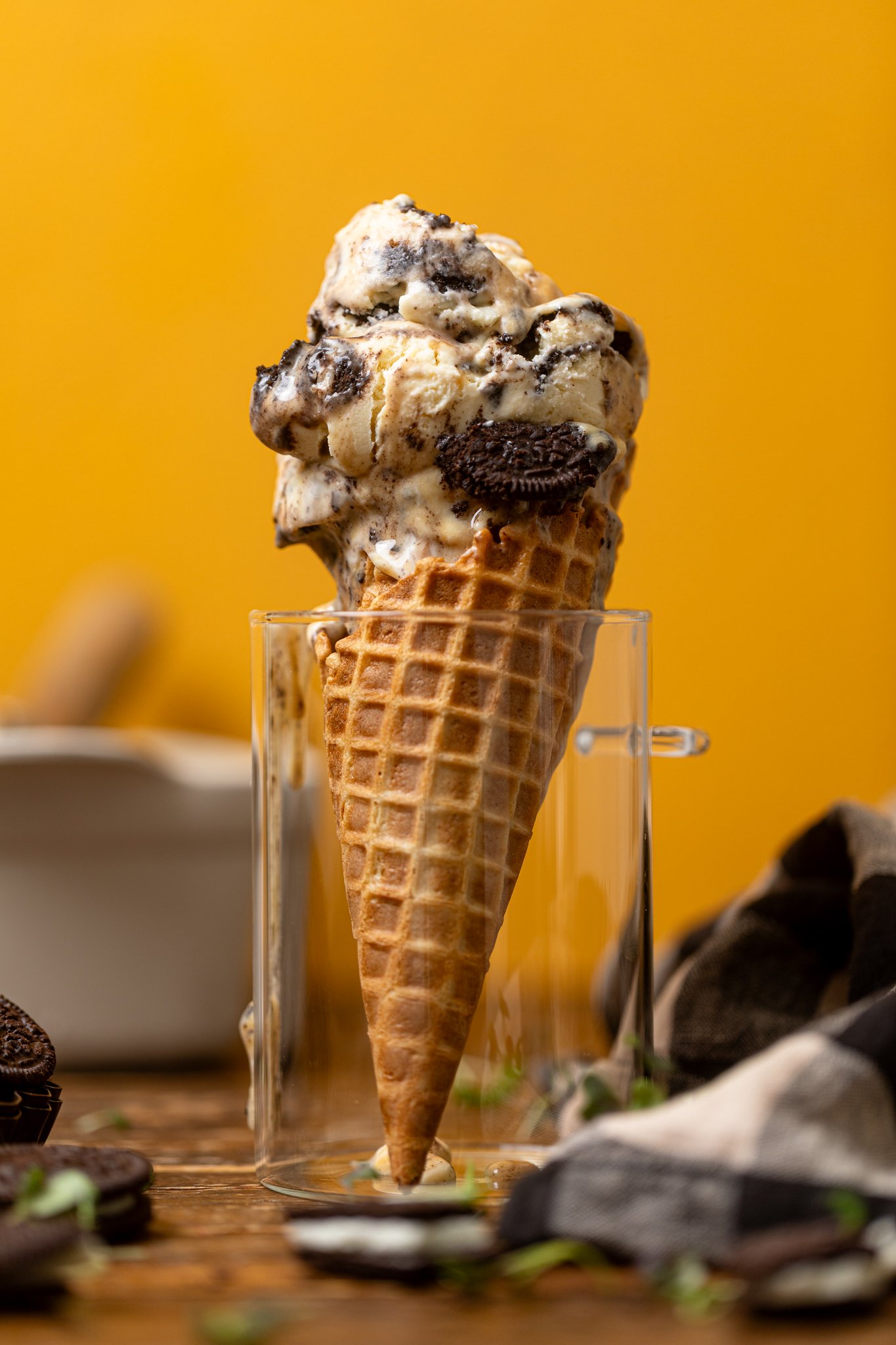 No-Churn Salted Caramel Oreo Ice Cream on a cone in a glass jar with Oreo cookies on the side.