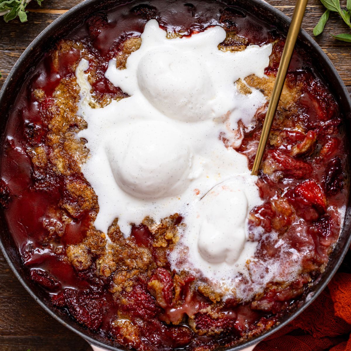 Southern Strawberry Dump Cake with ice cream and a gold serving spoon.