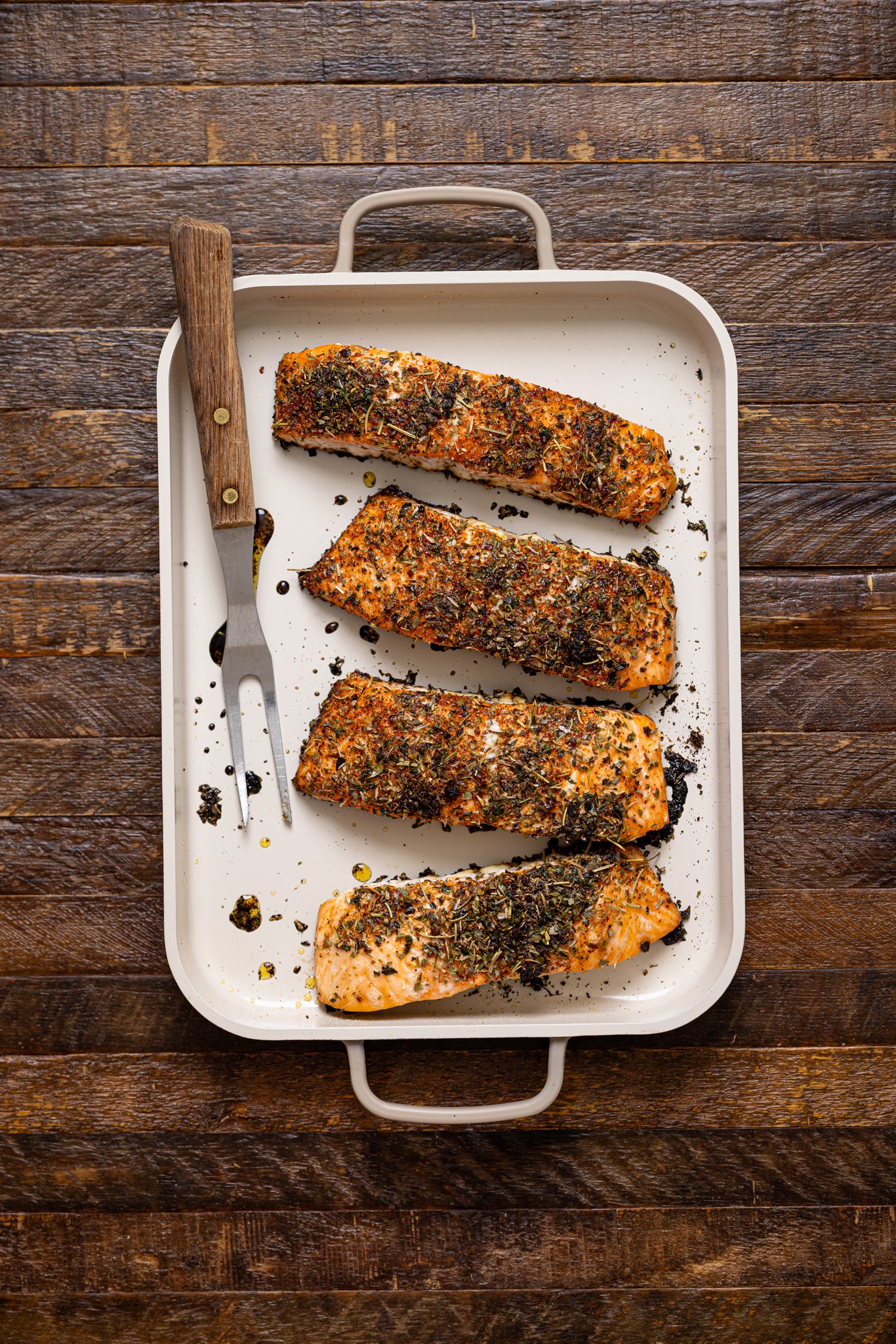Roasted salmon fillets on a baking griddle with a fork.