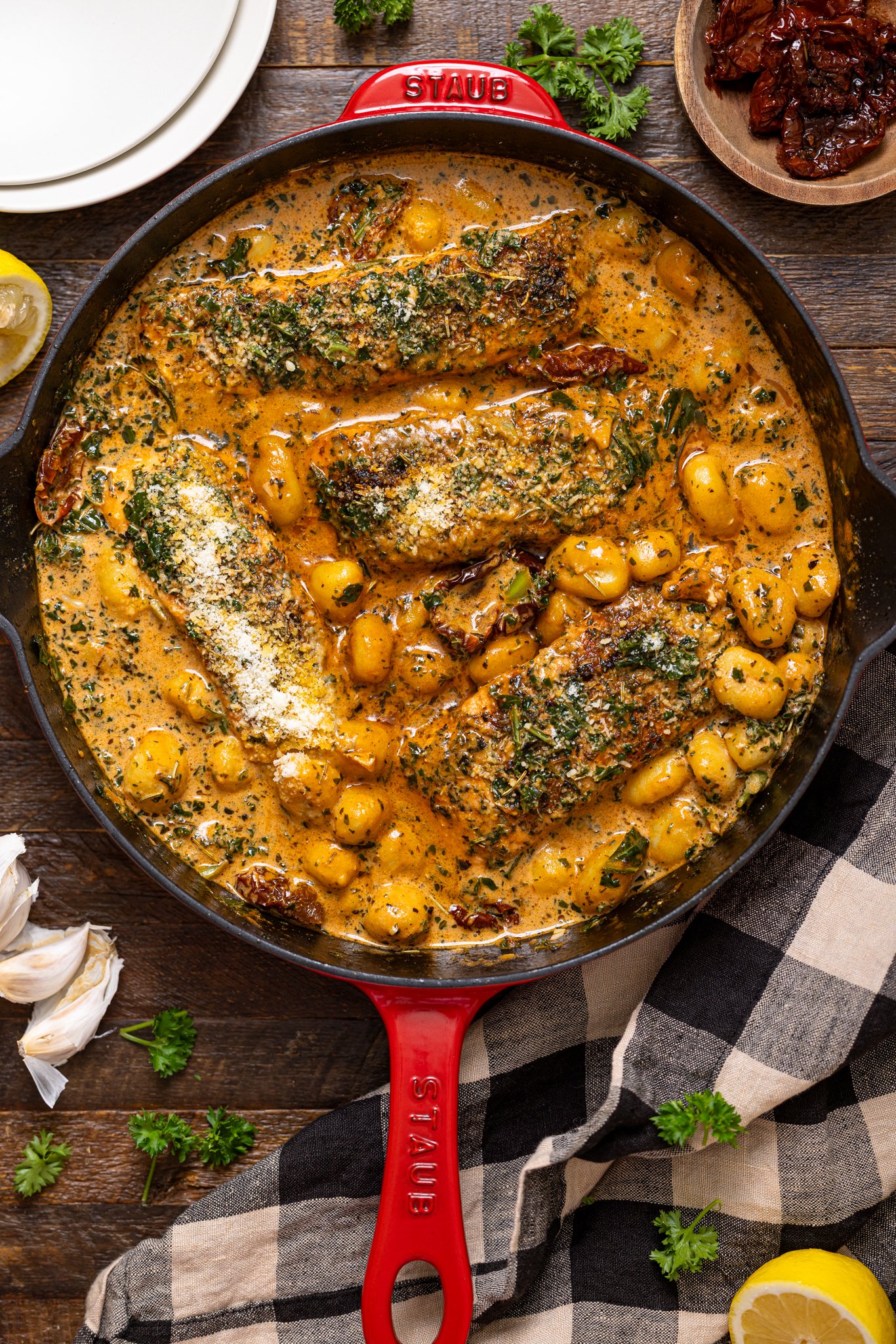 The Best Tuscan Marry Me Salmon in a skillet with garnish and plates.
