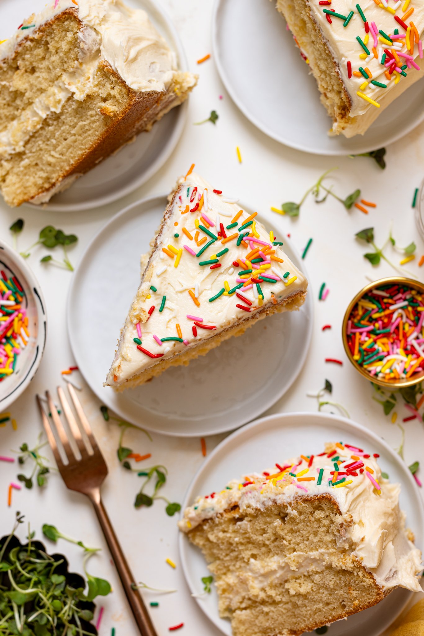 Cake slices on plates with a fork and rainbow sprinkles.