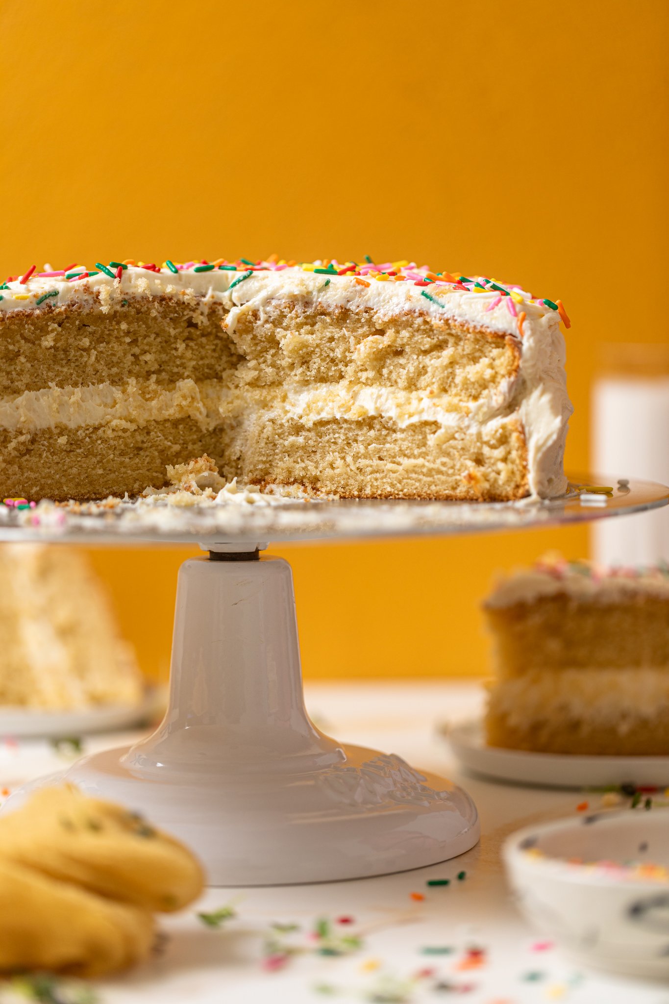 My Fave Vanilla Birthday Cake cut and sliced on a cake stand.