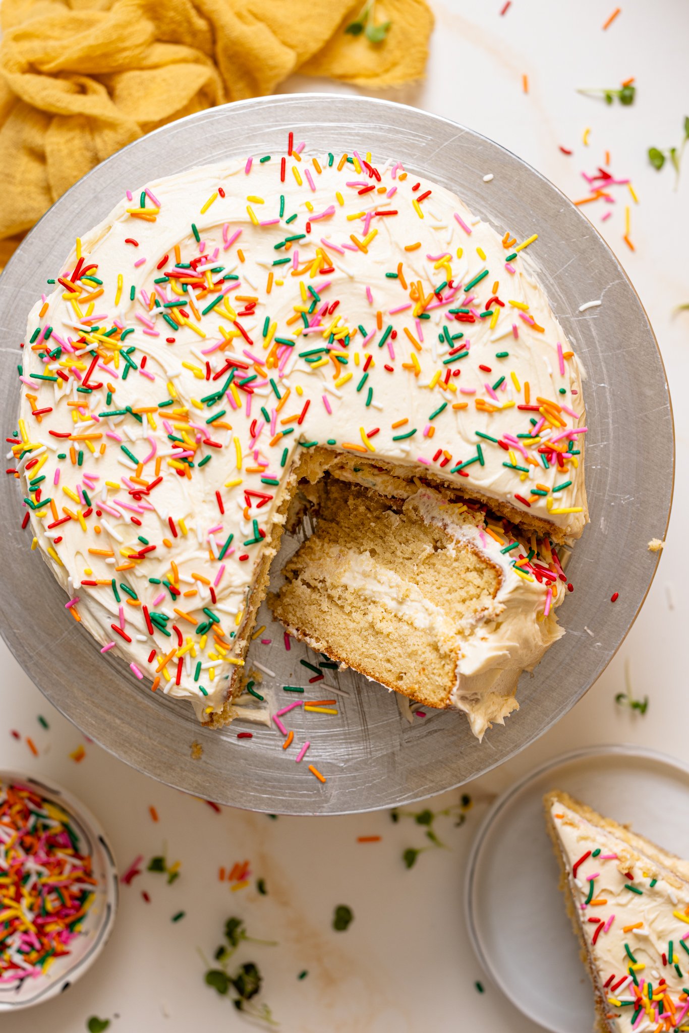 My Fave Vanilla Birthday Cake on a cake stand with slices cut.