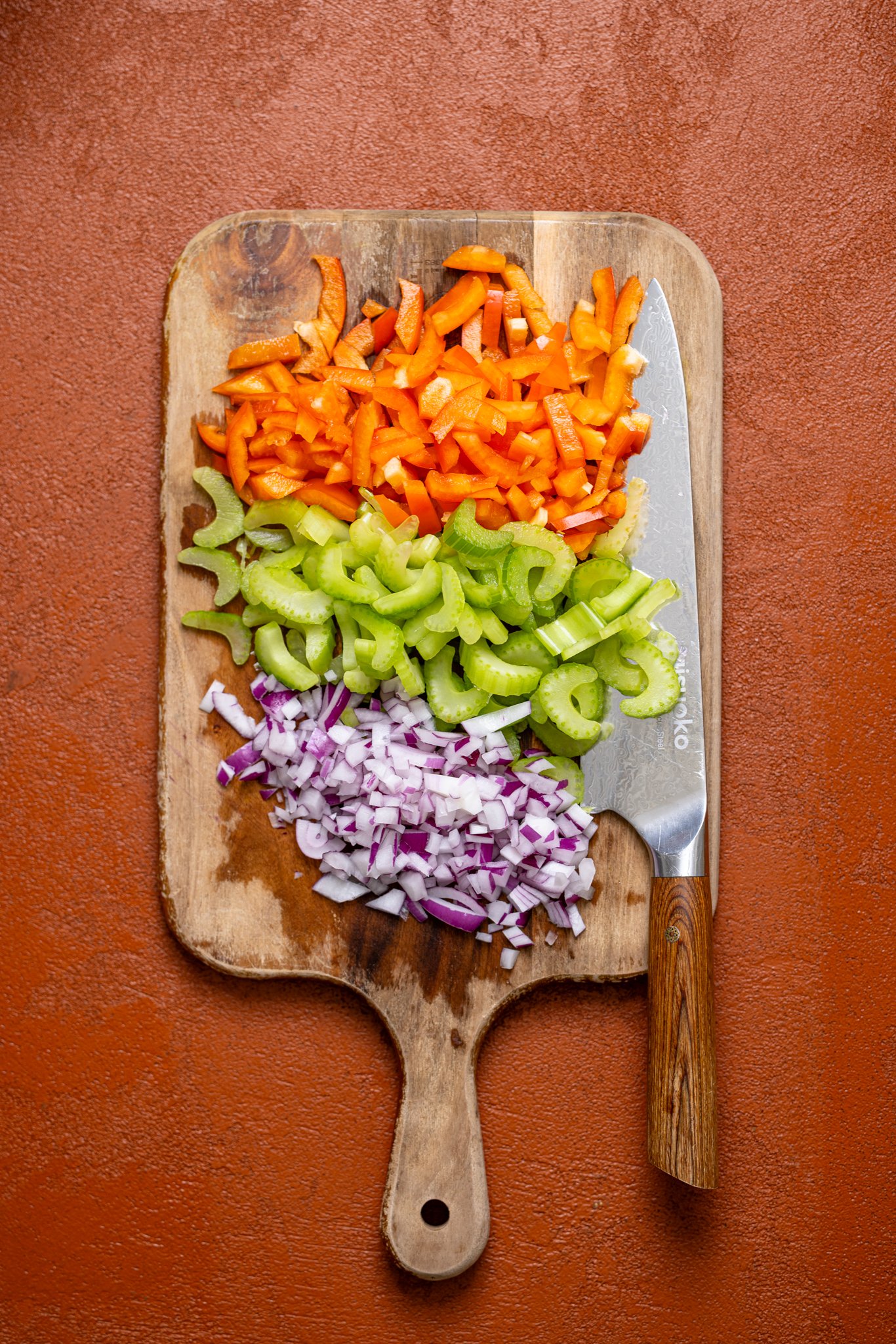 Chopped veggies on a cutting board with a knife.