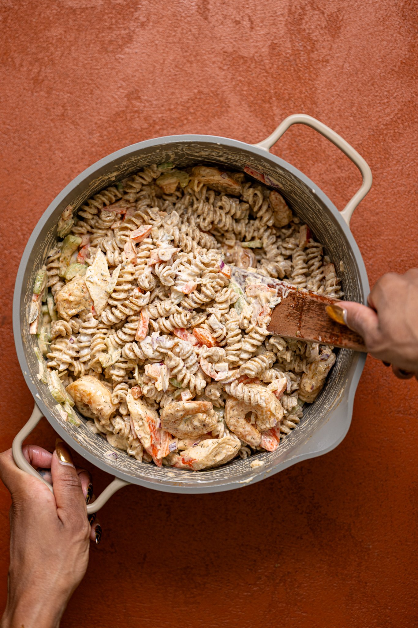 All ingredients being mixed together with a wooden spoon with woman hands.