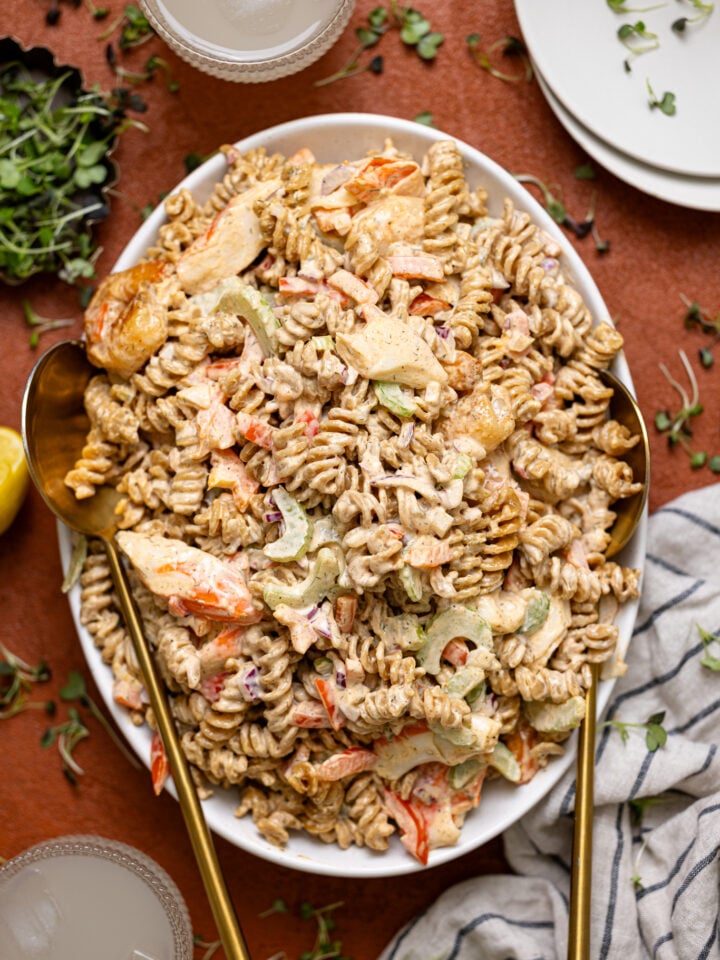 Best Seafood Salad Recipe on a platter with serving spoons and a drink.