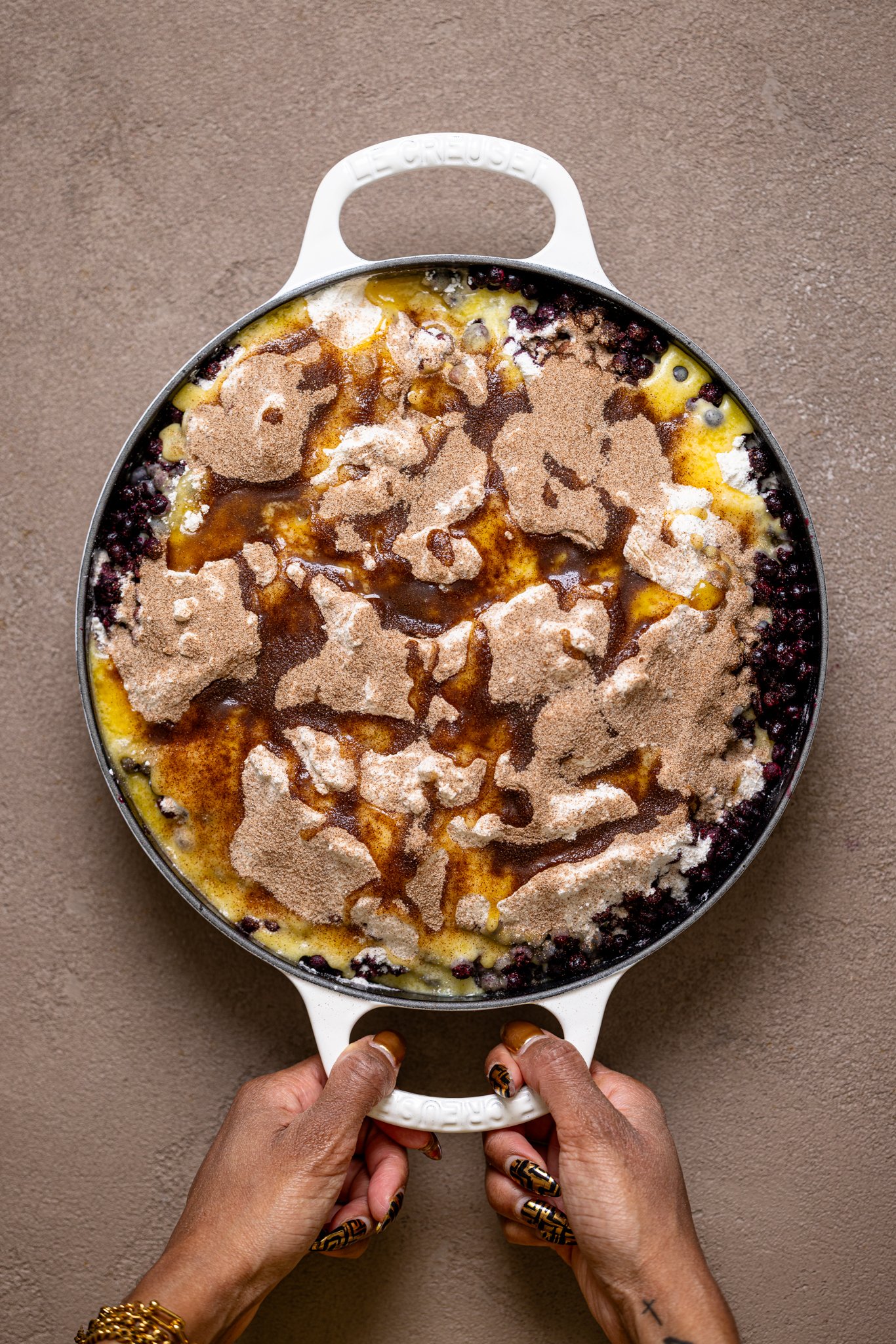 Ingredients assembled in white skillet being held by hands.