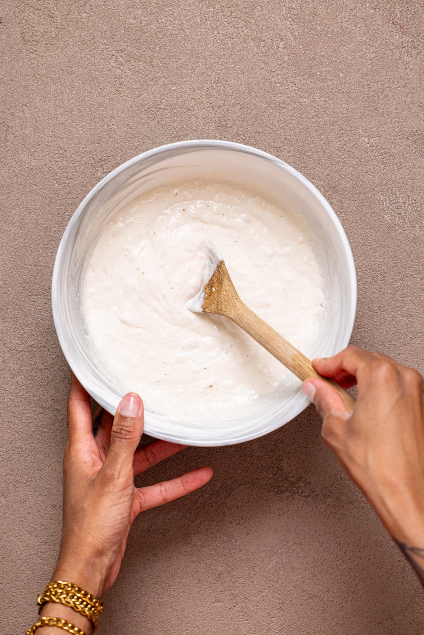 Donut batter being mixed together in a bowl with wooden spoon.