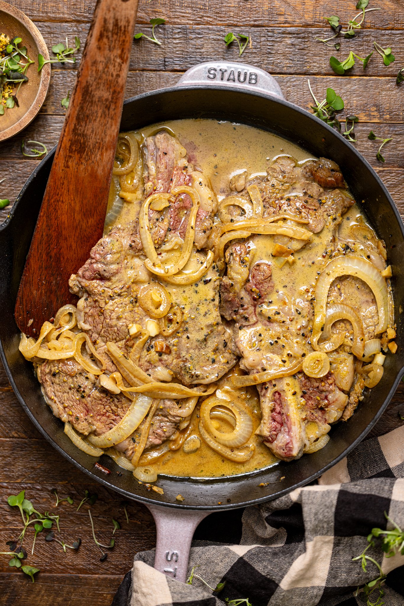 The Best Southern Smothered Steak in a skillet with a wooden spoon.