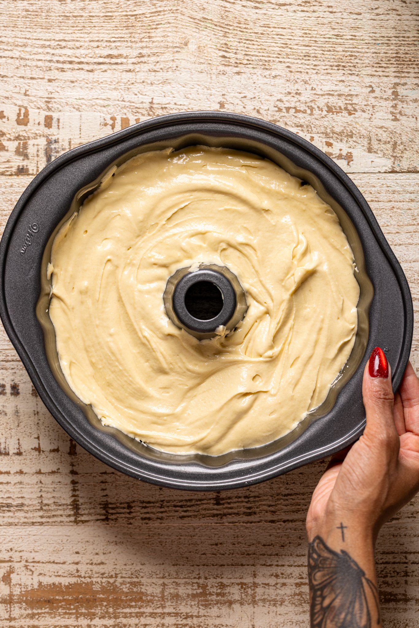 Cake batter in a bundt pan being held by woman hand.