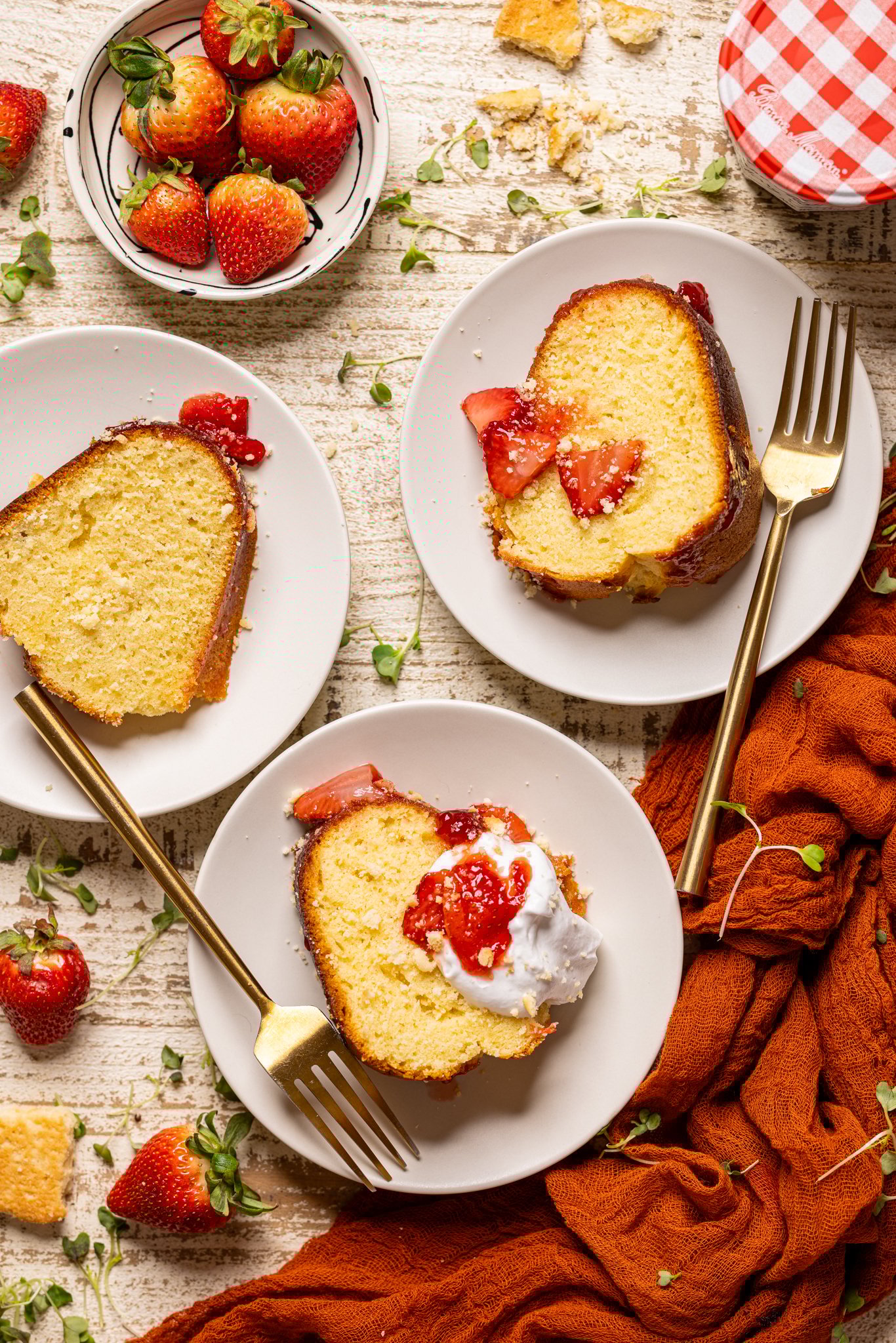 Strawberry Shortcake Bundt Cake slices on a three plates with forks and strabwerries.