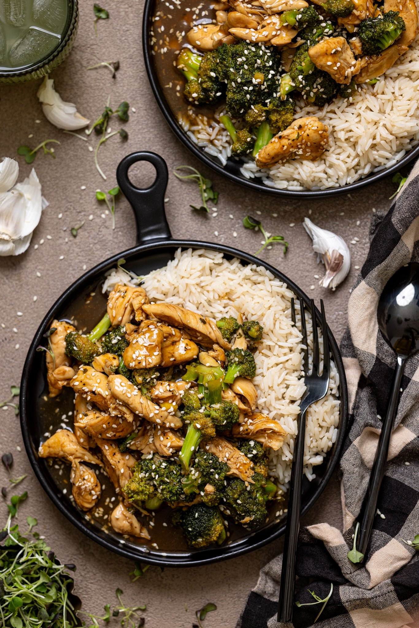 Two plates of Take Out Honey Garlic Chicken with utensils. 