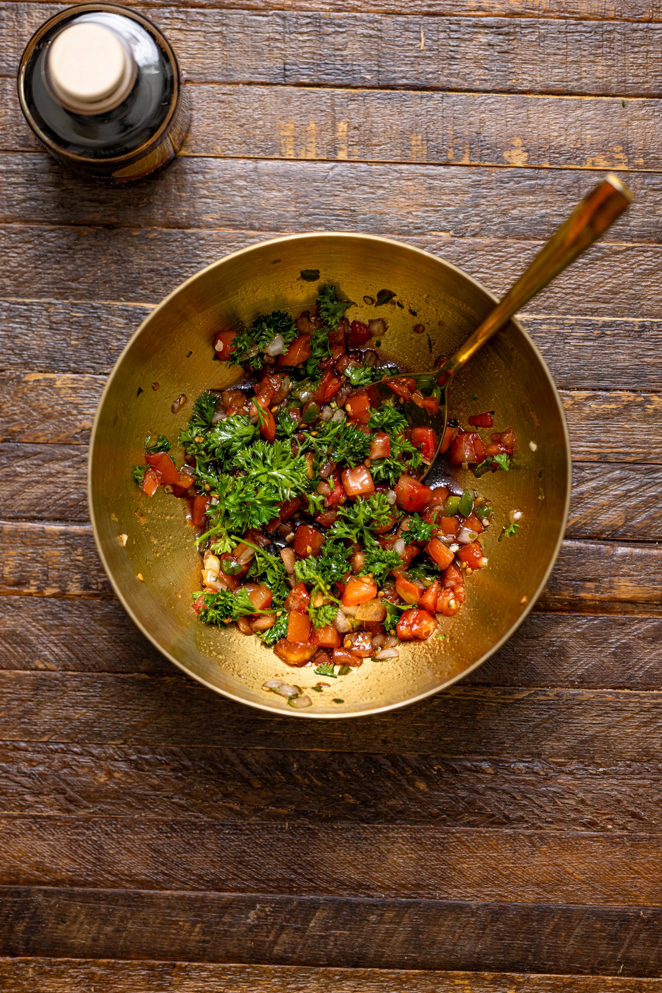 Bruschetta topping ingredients in a bowl with a spoon.