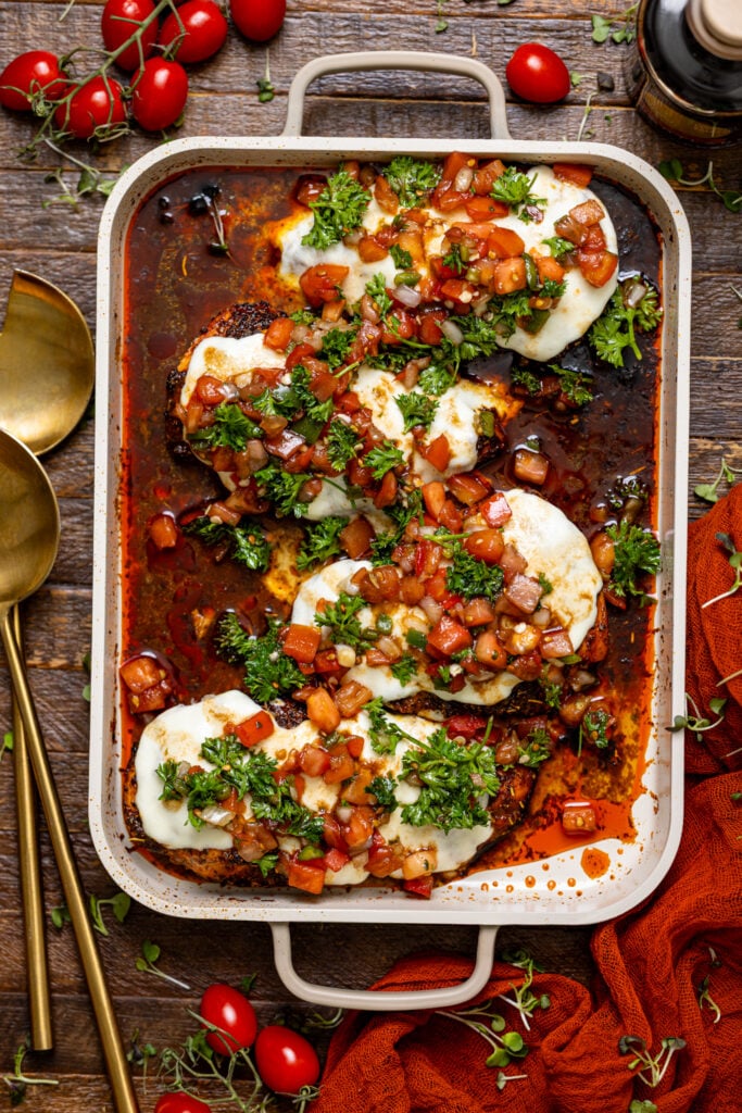 Weeknight Bruschetta Chicken Recipe on a baking griddle with serving spoons.