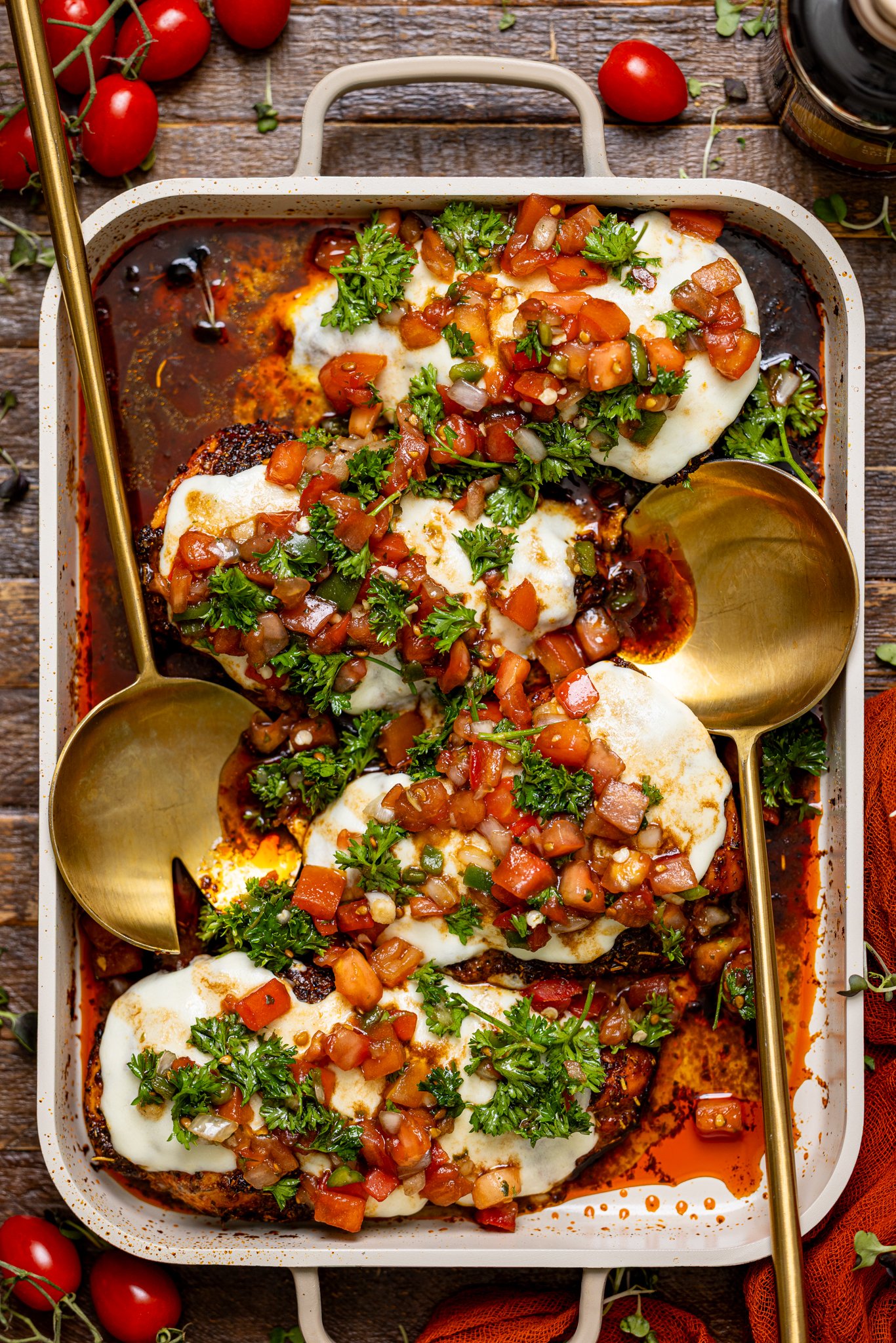 Weeknight Bruschetta Chicken Recipe on a griddle baking dish with spoons.