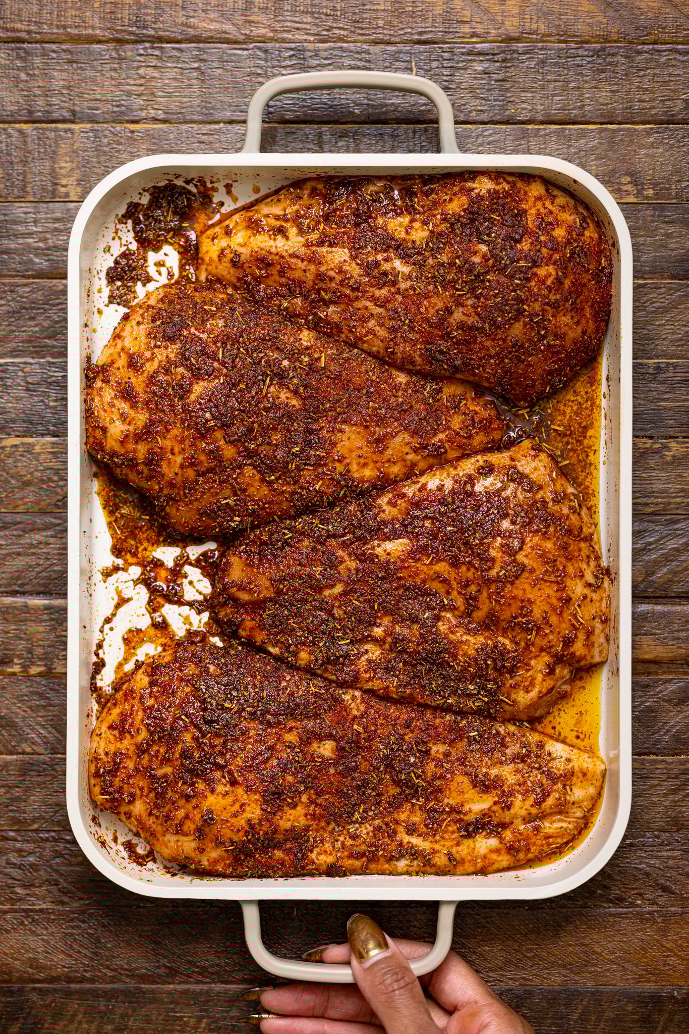 Seasoned chicken breasts on a baking griddle.