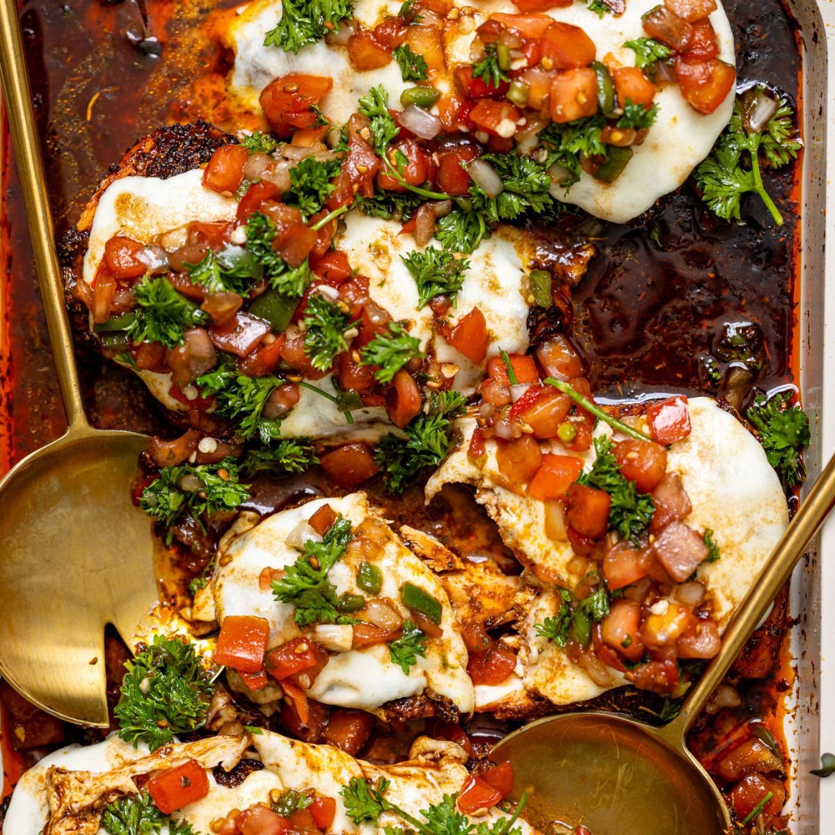 Weeknight Bruschetta Chicken Recipe on a baking griddle with serving spoons.