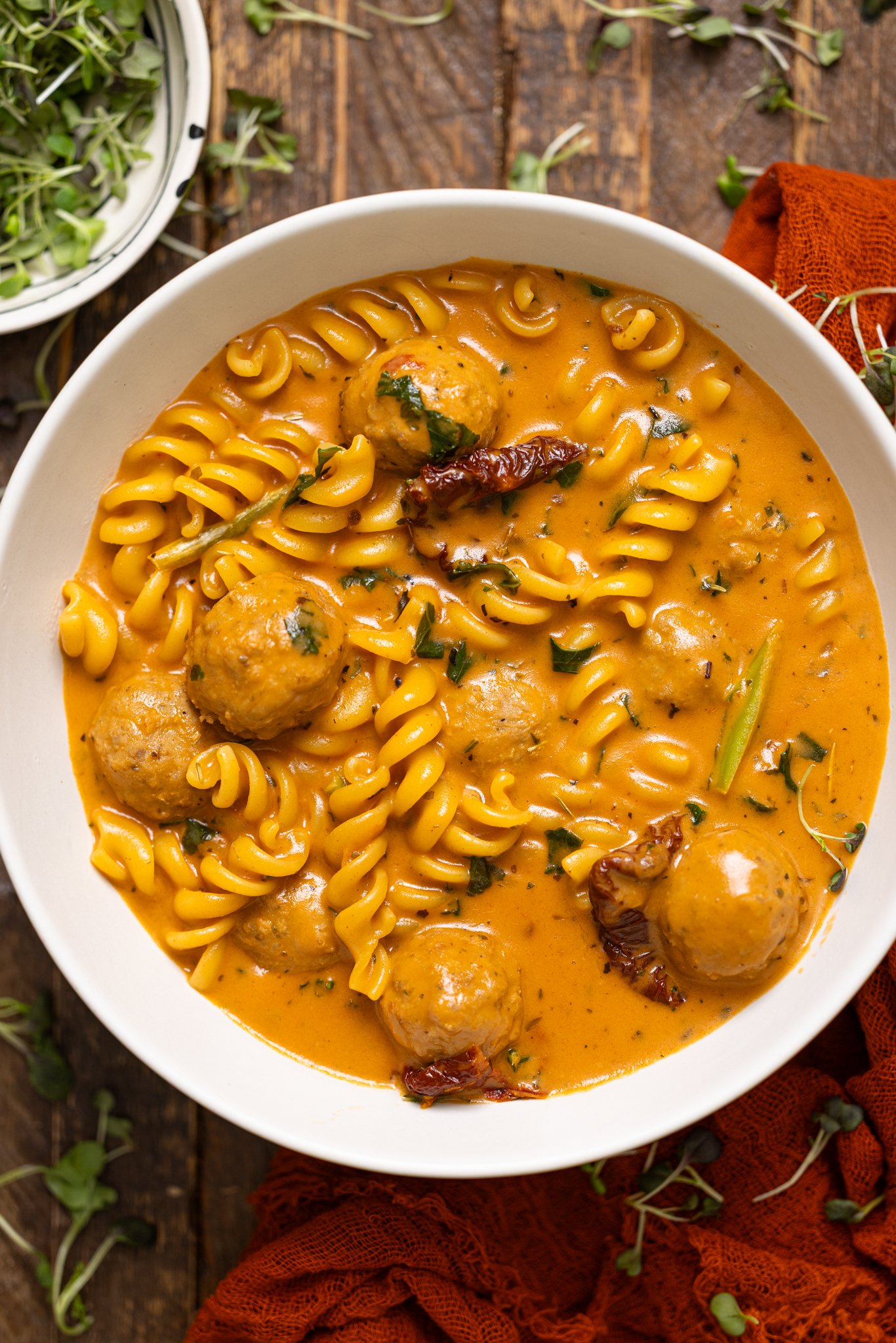 A bowl of Hearty Tuscan 'Marry Me' Meatball Soup on a brown wood table.