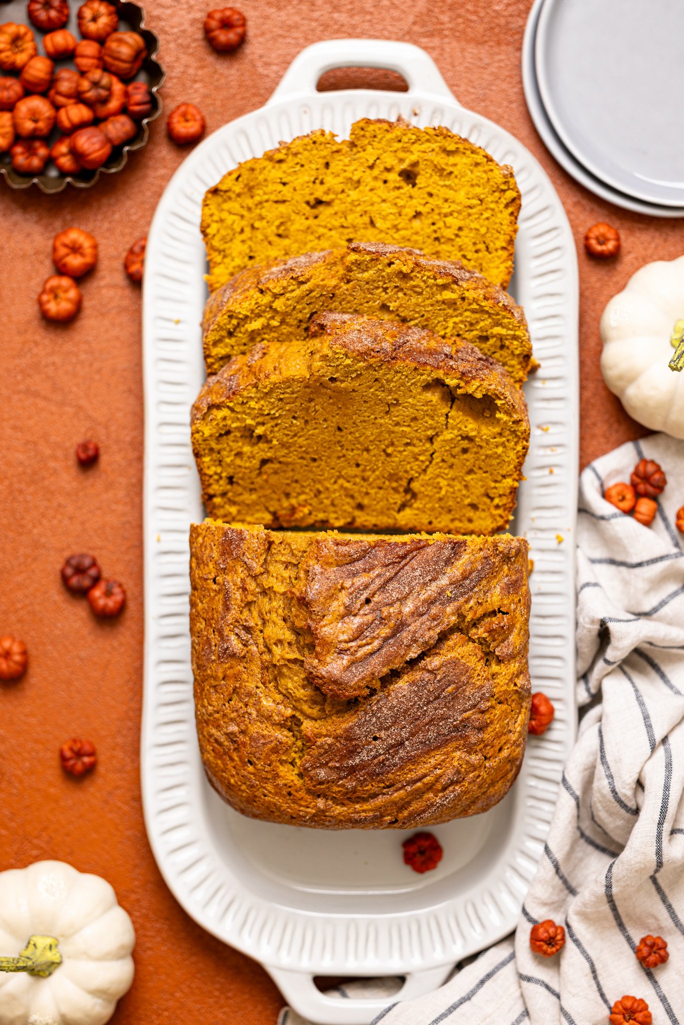 Comforting Pumpkin Chai Latte Bread on a platter sliced with pumpkin decor.