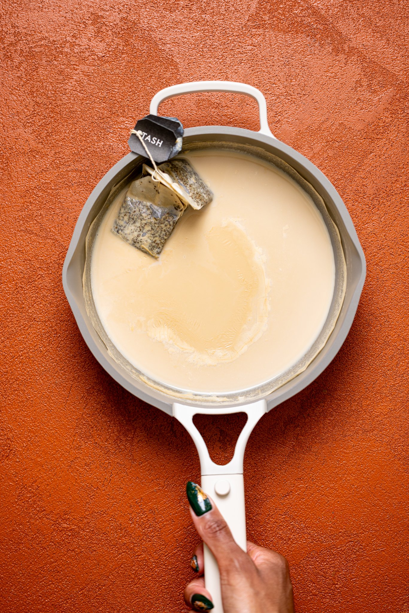 Brewed chai tea in a skillet being held by woman hands.