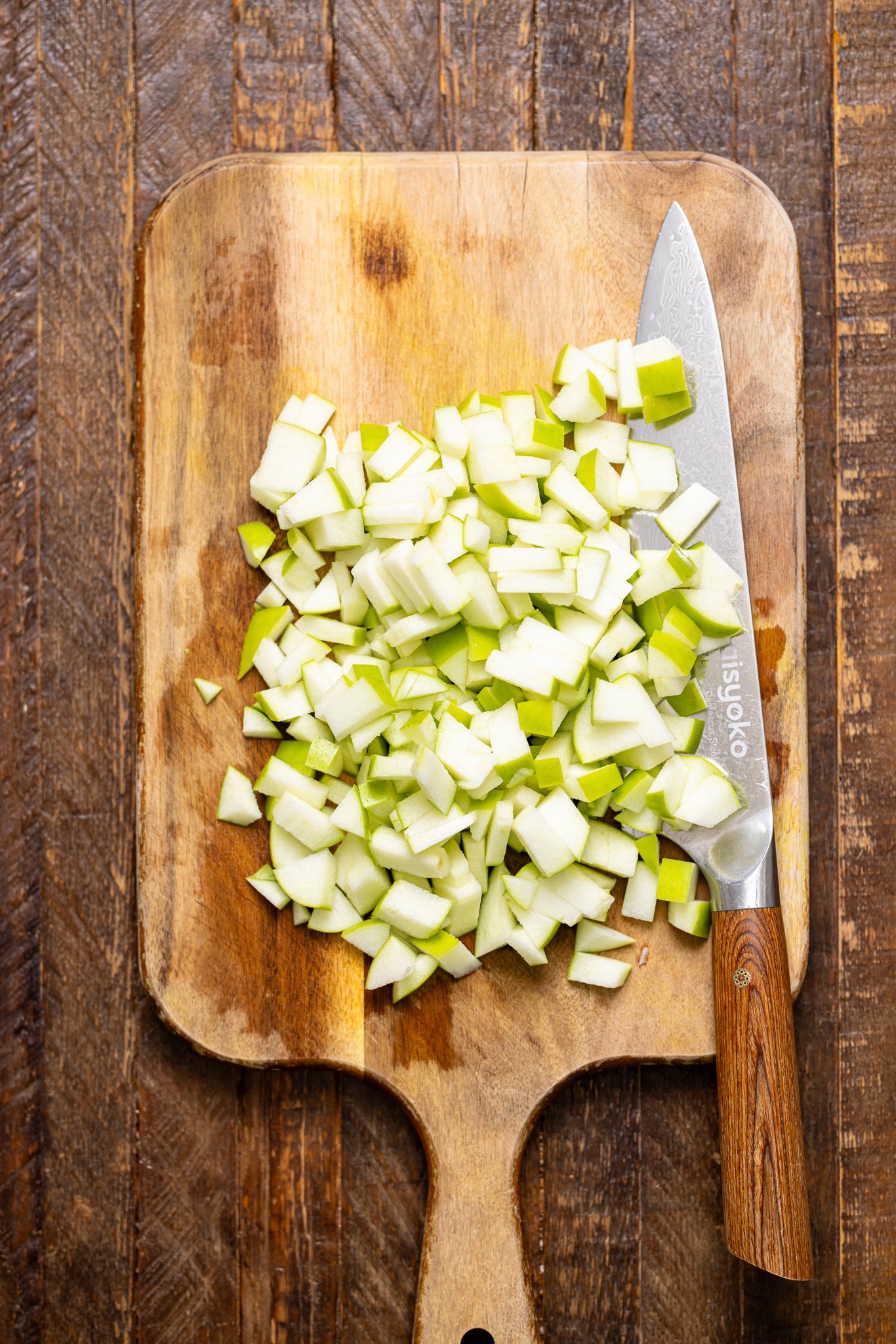 Diced apples on a cutting board with a knife.