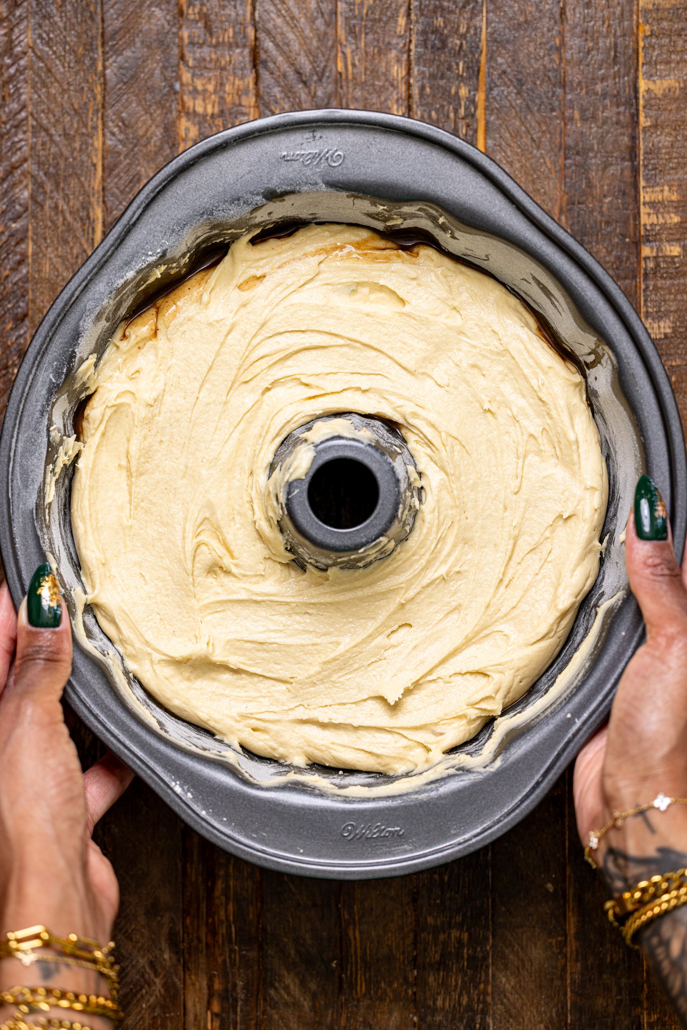 Cake batter in a bunt cake being held by woman hands.