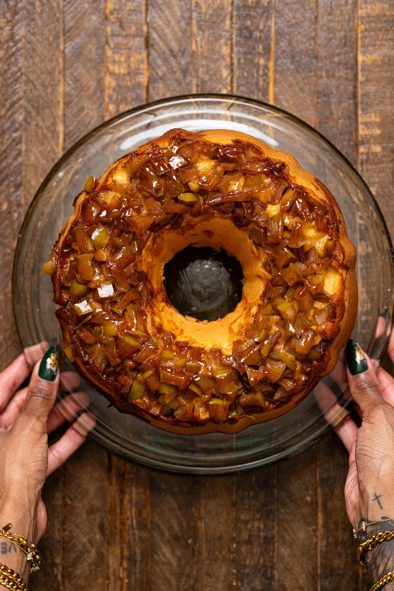 Baked The Best Apple Pie Bundt Cake on a cake stand being held by woman hands.