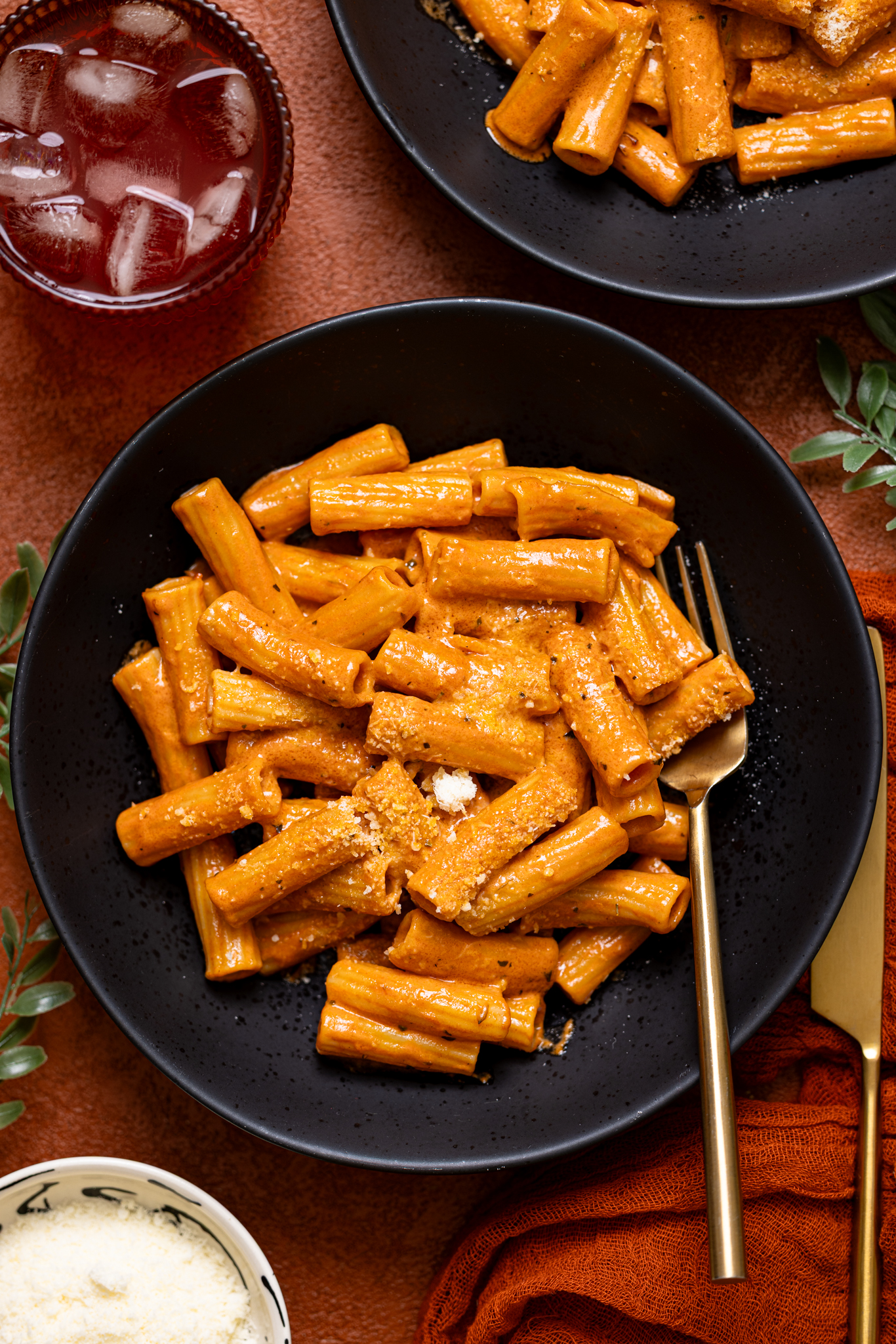 Two plates of My Go-to Weeknight Alla Vodka Pasta with a fork and drink.